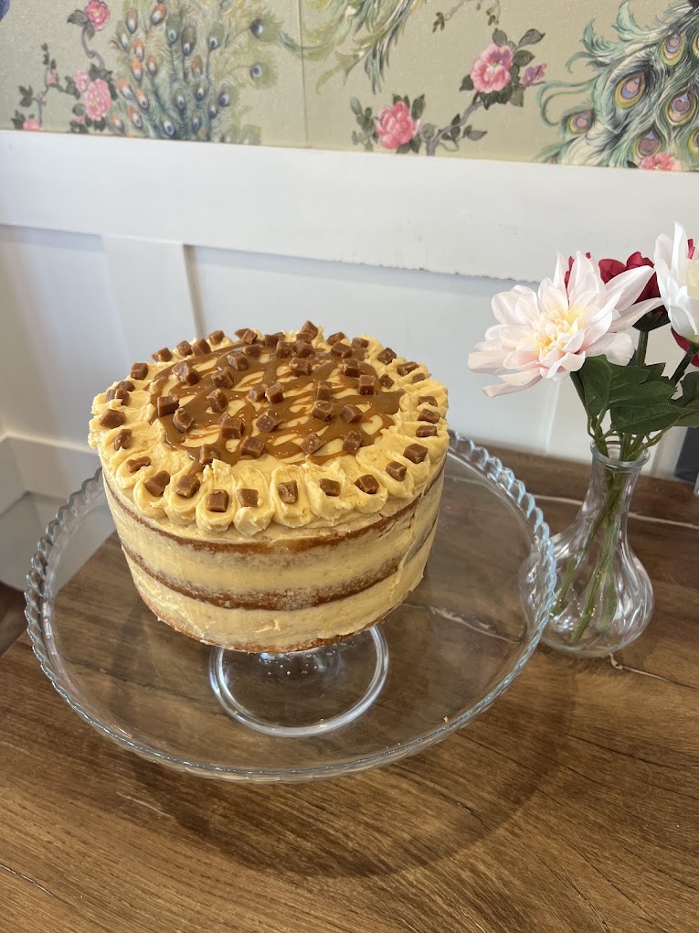 A salted caramel layer cake on a glass cake stand